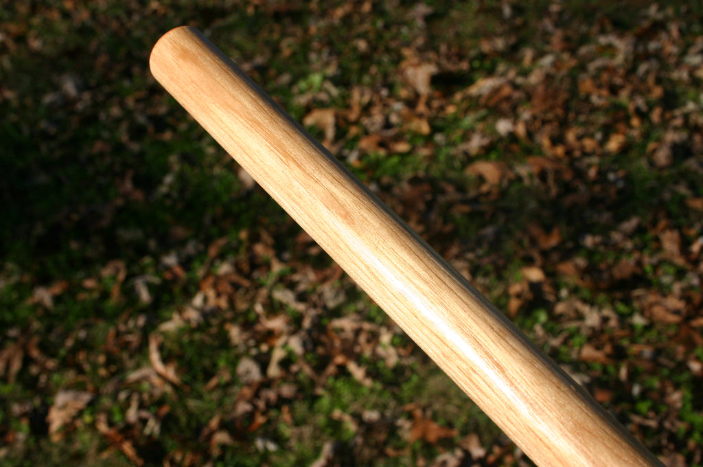 A Hickory martial arts staff with fall foliage in the background.